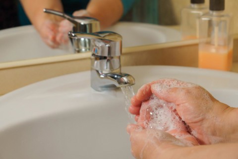 Closeup of a woman washing her hands with liquid soap suds in the bathroom sink. Hand hygiene from