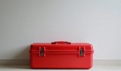 A bright red toolbox with latches closed, set against a plain light background AI generated