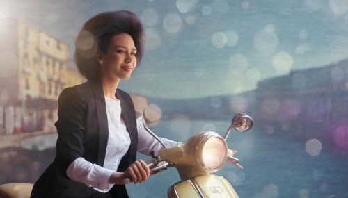 Elegant woman on a vintage scooter with pastel tones and soft bokeh lights, blurry moody landscaped