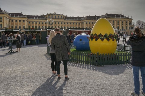 A couple looks at a large, decorative Easter egg in front of the magnificent Schoenbrunn Palace
