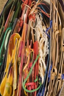 Top view and close-up of red, yellow, green, blue, folded paper gift bags with rope handles, Studio