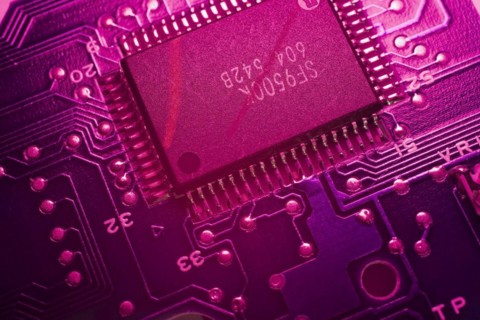 Close-up of purple lighted electronic computer circuit board with memory chip lines and silver