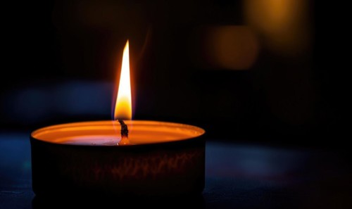 Close-up of a candle's gentle flicker illuminating a serene setting AI generated