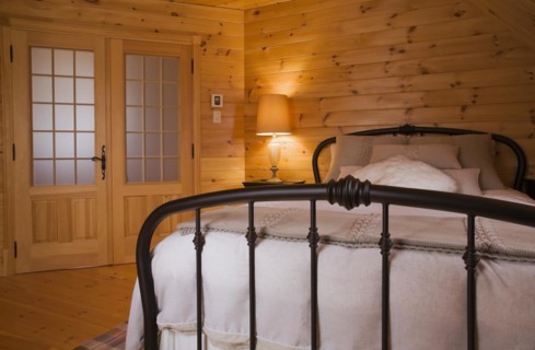 Queen size bed with white bedspread, throw and pillows, tubular cast iron headboard and footboard