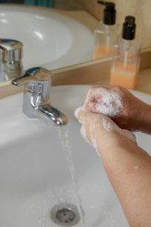 Closeup of a woman washing her hands with liquid soap suds in the bathroom sink. Hand hygiene from