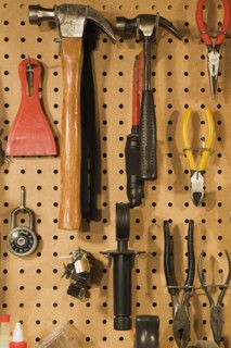 Assorted hand tools that include a small and medium hammer, red needle nose pliers, yellow wire