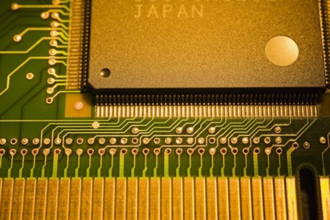 Close-up of golden yellow and green lighted electronic computer circuit board witrh memory chip,