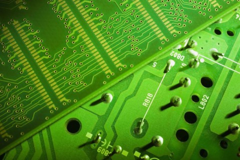 Close-up of fluorescent green lighted electronic computer circuit boards with silver solder points