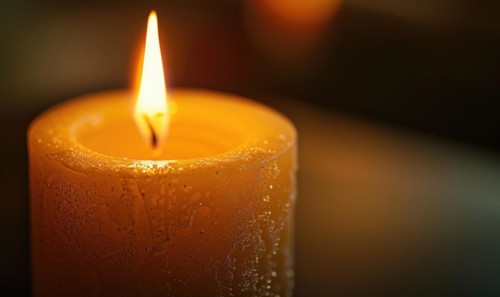 Close-up of a candle's gentle flicker illuminating a serene setting AI generated