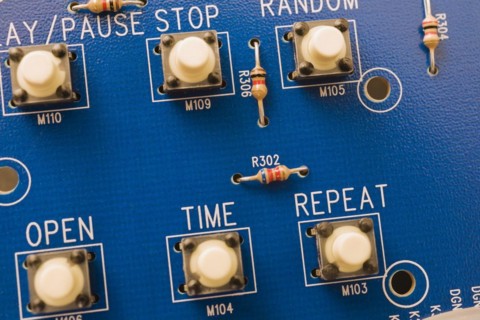 Close-up of blue electronic DVD player circuit board with function push button controls, Studio