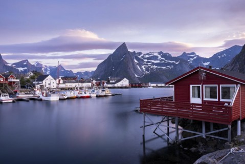 The village of Hamnoy. In the foreground, a typical red wooden house (rorbuer) on wooden stilts.