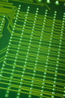 Close-up of fluorescent green lighted electronic computer circuit board with lines and silver