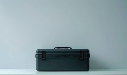 A dark, sturdy toolbox with a closed latch on a simple gray background AI generated