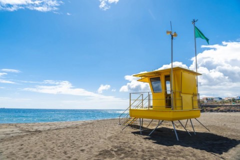 Yellow lifeguard tower in California with green flag