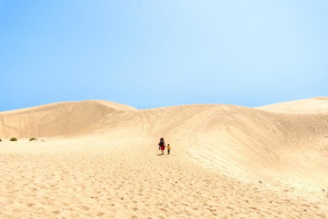 Father and son on vacation smiling in the dunes of Maspalomas, Gran Canaria, Canary Islands
