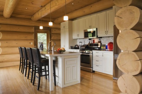 White painted wooden cabinets and island with dark brown wood and leather high back bar stools in
