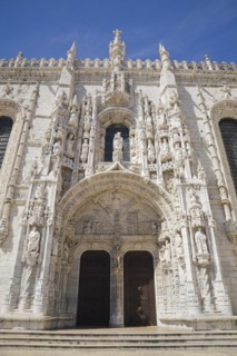Jeronimos Monastery facade with arched front entrance door decorated with carved sculptures,