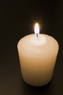 Close-up of white wax candle with bright lit flame on black background, Studio Composition, Quebec,
