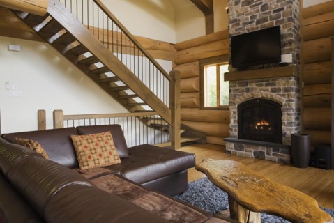 Brown leather L-shaped sofa and wooden coffee table in front of lit nuanced tan and brown natural