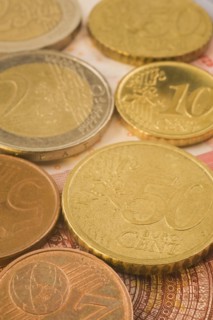 Close-up of gold and copper colored assorted five, ten, fifty Euro cent coins on top of Euro bank