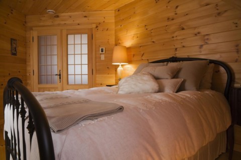 Queen size bed with white bedspread, throw and pillows, tubular cast iron headboard and footboard