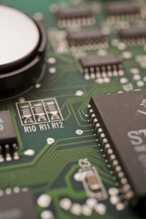 Close-ip of green computer circuit board with hard disc, memory chip, silver solder points and