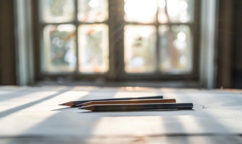 Graphite pencils and white paper illuminated by natural through a window AI generated