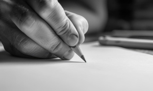 A hand holding a graphite pencil poised over a blank sheet of white paper AI generated