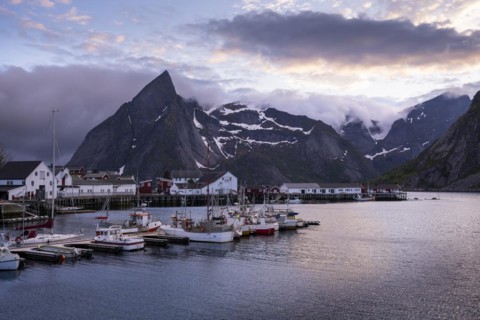 The village of Hamnoy. Houses and boats in a small harbour. Mount Olstinden in the background. At