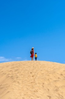 Mother and child smiling in the dunes of Maspalomas in summer, Gran Canaria, Canary Islands