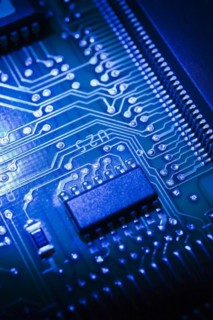 Close-up of blue lighted electronic computer circuit board with microchip, silver solder points and