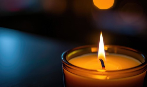 Close-up of a candle's gentle flicker illuminating a serene setting AI generated