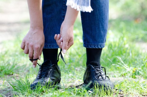 Woman Tying Shoelaces on a Path with Grass