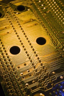 Close-up of golden and green lighted electronic computer circuit board with silver solder points