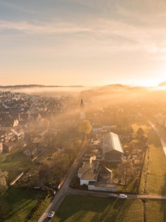 A town awakes in the light of sunrise, shrouded in light fog, Gechingen, Black Forest, Germany,