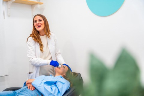 Happy doctor during a beautician treatment in the clinic with a patient