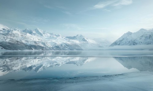 A frozen lake in the depths of winter, surrounded by snow-capped mountains AI generated