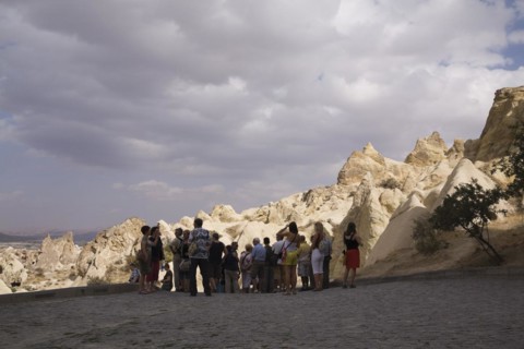 Tourists visiting the rock-cut cave dwellings in Goreme valley, Cappadocia region, Turkey, Asia
