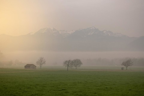 A landscape in the morning mist with a small hut and mountains in the background, Neubeuern,