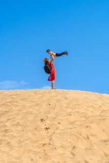 Mother lifting child smiling in the dunes of Maspalomas in summer, Gran Canaria, Canary Islands