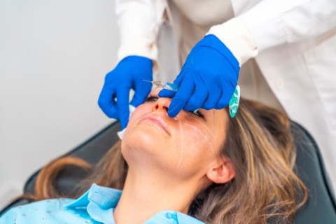 Doctor cleaning the injection area with a cotton pad on the patient's face before administering