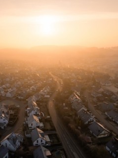 Sunrise casts a soft light on a town and its church towers in the distance, Gechingen, Black