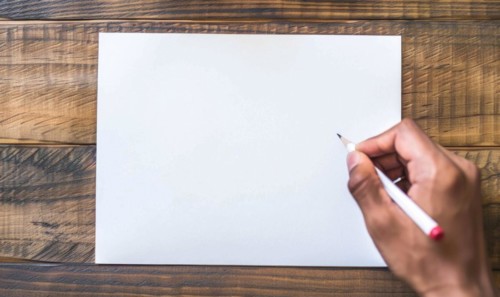 A hand holding a graphite pencil poised over a blank sheet of white paper AI generated