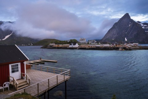 View of Sakrisoy with its typical yellow or ochre-coloured wooden houses by the sea, with Mount