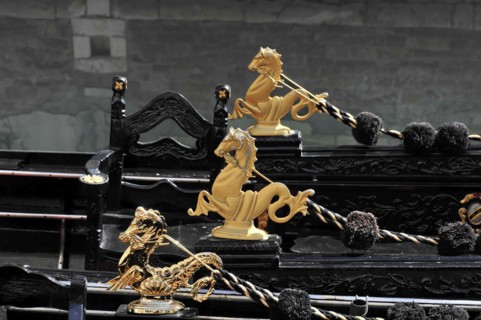 Several gilded sculptures on the black gondolas against a dark background, Venice, Veneto, Italy,