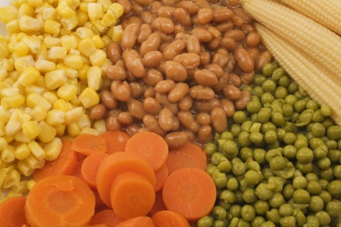 Close-up of mixed cooked vegetables that include brown baked beans, green peas, orange carrots and
