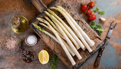 White asparagus on a rustic background with olive oil, lemon wedge and spices, fresh white