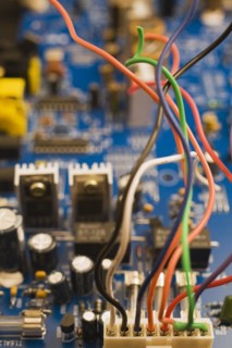 Close-up of colorful insulated electrical wires and blue computer circuit board with capacitors and