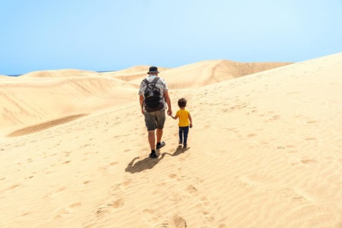 Father and son on vacation smiling in the dunes of Maspalomas, Gran Canaria, Canary Islands