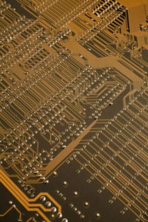 Close-up of golden orange lighted electronic computer circuit board with lines and silver solder